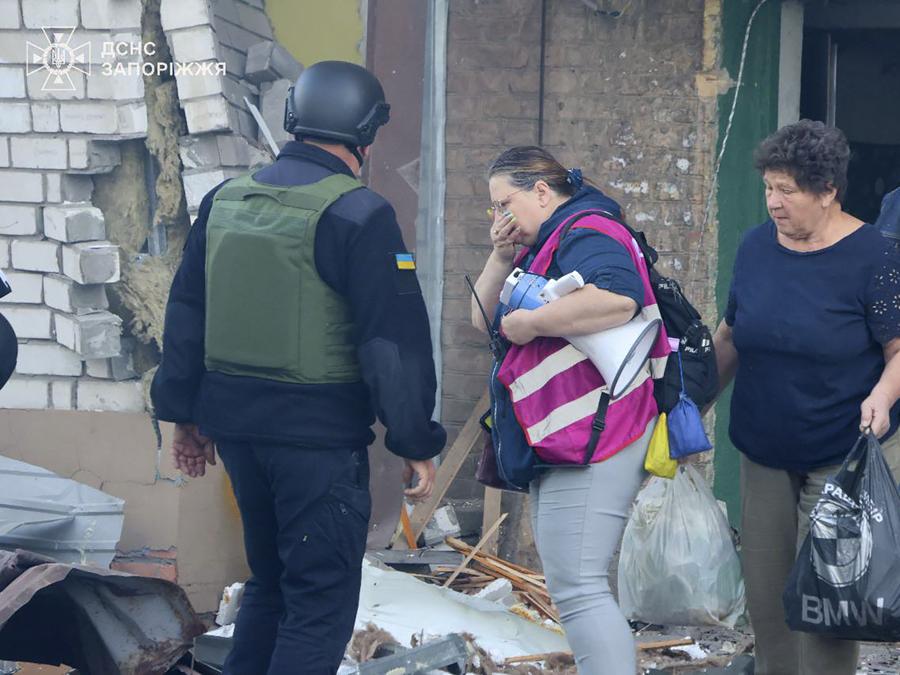 I residenti con i loro effetti personali lasciano la loro casa in rovina dopo che la Russia ha attaccato la città con bombe guidate durante la notte a Zaporizhzhia, Ucraina. (Ukrainian Emergency Service via AP)
