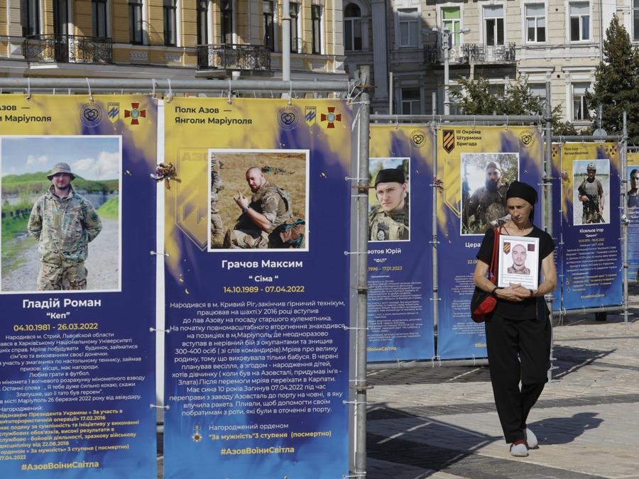 Una donna passa davanti ai manifesti con i ritratti dei soldati ucraini caduti esposti in piazza Sophiivska, durante la processione “Onore ai vivi, ricorda i caduti” per il “Giorno dei difensori dell’Ucraina”, a Kiev, Ucraina. EPA/SERGEY DOLZHENKO