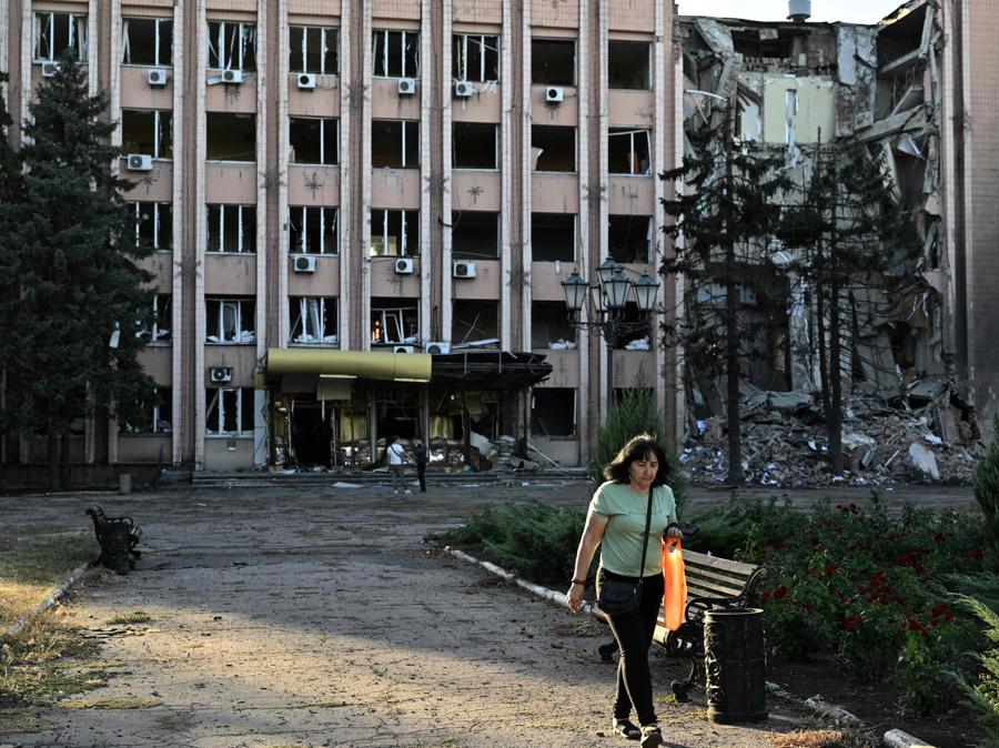Una donna cammina davanti a un edificio amministrativo, gravemente danneggiato dopo un attacco russo notturno nella città di Dobropillia, nella regione di Donetsk. (Photo by Genya SAVILOV / AFP)