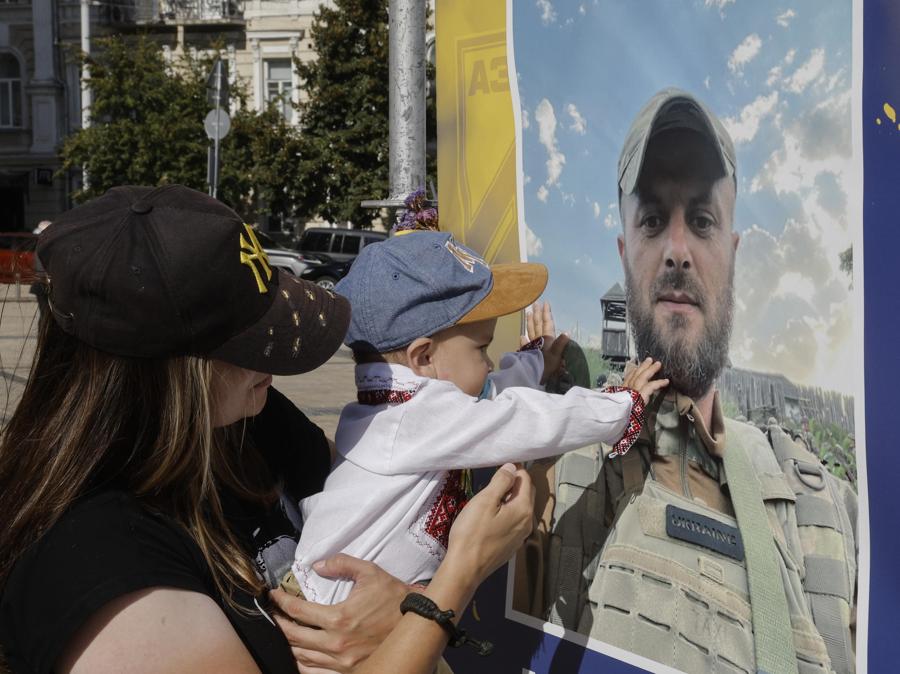 Un bambino  vicino a un poster con il ritratto del padre caduto esposto in piazza Sophiivska, durante la processione “Onore ai vivi, ricorda i caduti” per il “Giorno dei difensori dell’Ucraina”, a Kiev, Ucraina. EPA/SERGEY DOLZHENKO