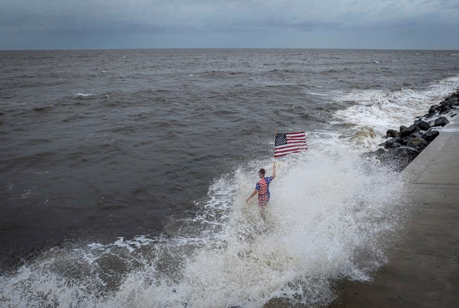 Un uomo sventola  una bandiera americana e viene travolto da un’onda che si infrange mentre l’uragano Helene si intensifica. (Reuters)