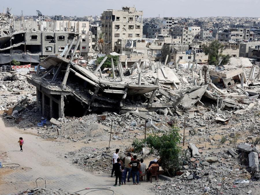 Palestinesi seduti accanto alle macerie delle case distrutte durante l’offensiva militare israeliana, a Khan Younis, nella Striscia di Gaza meridionale. (REUTERS/Mohammed Salem/File Photo)