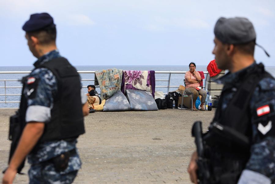 I membri delle forze di sicurezza libanesi controllano gli sfollati che hanno allestito rifugi di fortuna sul lungomare di Beirut per trasferirli. Dall’inizio dei combattimenti  circa 1,2 milioni di persone hanno deciso di fuggire. (Photo by AFP)