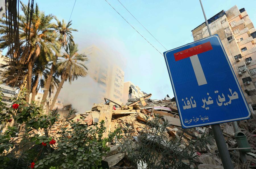Un uomo si erge sopra i detriti degli edifici distrutti dietro un cartello di strada senza uscita nel quartiere Haret Hreik, sobborgo meridionale di Beirut. (Photo by AFP)