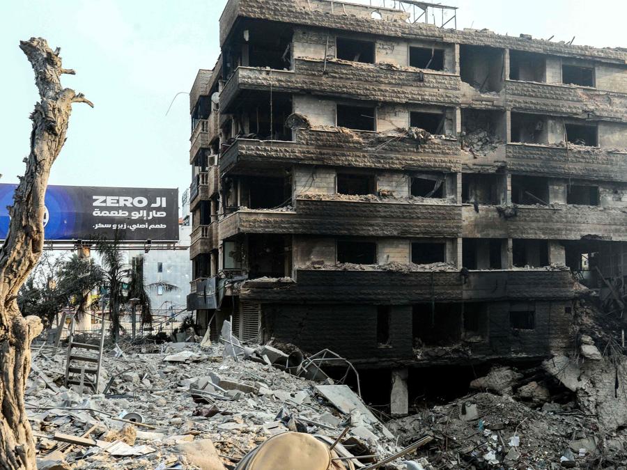 Un edificio distrutto  vicino a un cratere dovuto ad un attacco aereo israeliano notturno che ha preso di mira un sobborgo meridionale di Beirut. (Photo by AFP)
