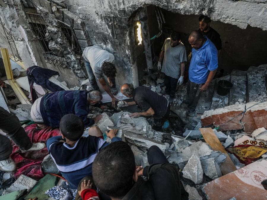 Palestinesi cercano corpi e sopravvissuti tra le macerie della casa distrutta della famiglia Al-Tilbany a seguito di un attacco aereo israeliano nel campo profughi di Al-Maghazi nella Striscia di Gaza. EPA/MOHAMMED SABER