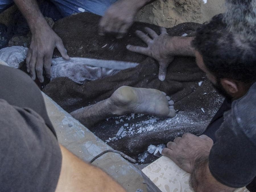 Palestinesi recuperano vittime tra le macerie di una casa distrutta della famiglia Shnaa a seguito di un attacco aereo israeliano nel campo profughi di Al-Maghazi nella Striscia di Gaza. EPA/MOHAMMED SABER