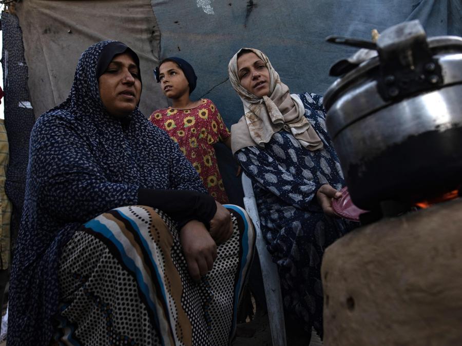 Donne palestinesi sfollate interne cucinano cibo fuori da una tenda in un campo a Khan Younis, nel sud della Striscia di Gaza. EPA/HAITHAM IMAD