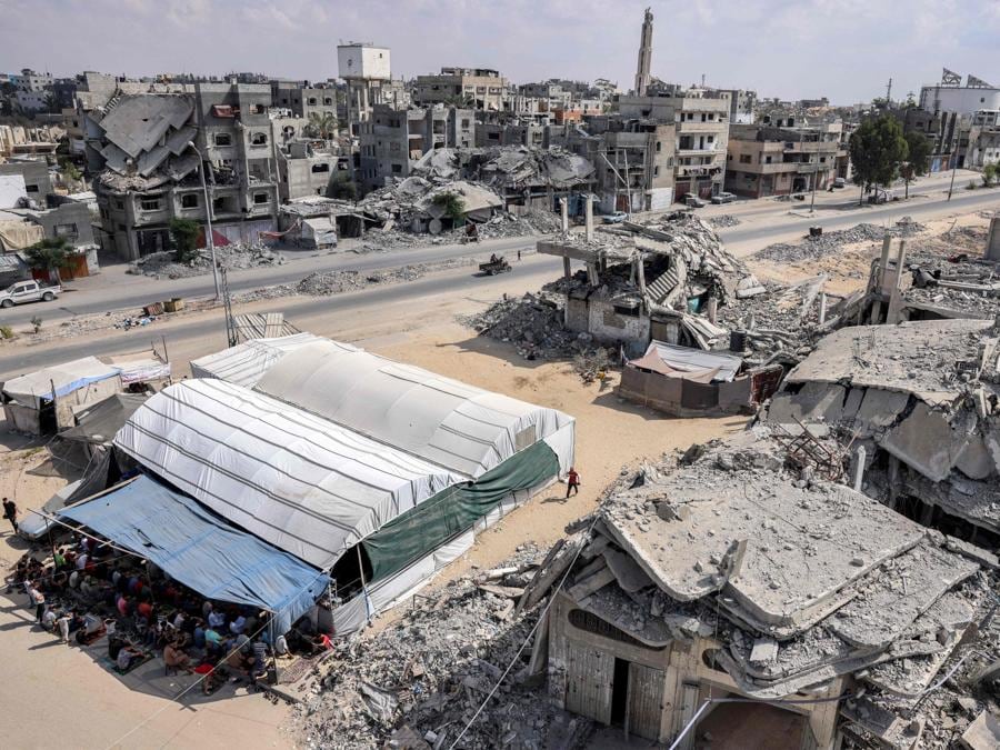I fedeli musulmani eseguono le preghiere settimanali del venerdì in una tenda recintata accanto agli edifici distrutti a Khan Yunis, nel sud della Striscia di Gaza. (Photo by BASHAR TALEB / AFP)