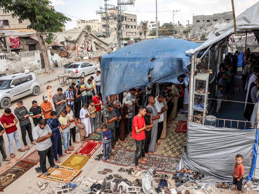 I fedeli musulmani eseguono le preghiere settimanali del venerdì in una tenda recintata accanto agli edifici distrutti a Khan Yunis, nel sud della Striscia di Gaza. (Photo by BASHAR TALEB / AFP)