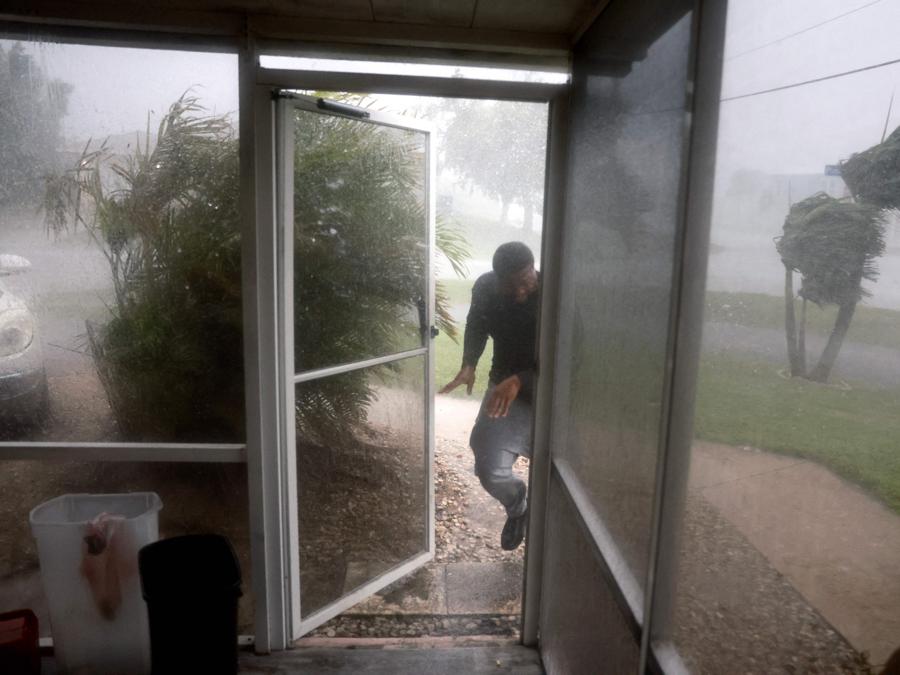 Un uomo corre sotto un temporale mentre carica la macchina per evacuare il suo appartamento prima dell’arrivo dell’uragano Milton il 9 ottobre 2024 a Fort Myers, Florida. (Photo by Joe Raedle / Getty Images North America / Getty Images via AFP)