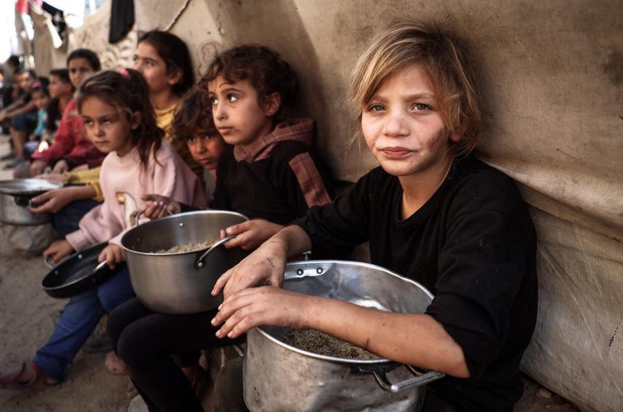 Bambini palestinesi raccolgono aiuti alimentari nel campo profughi di Bureij, nel centro della Striscia di Gaza. (AFP)