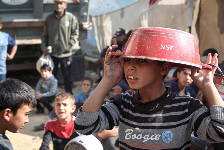 Bambini palestinesi raccolgono aiuti alimentari nel campo profughi di Bureij, nel centro della Striscia di Gaza. (AFP)