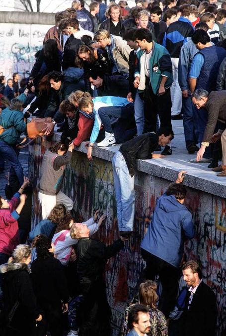 Centinaia di berlinesi esultanti si aiutano a vicenda per raggiungere entrambi i lati del Muro di Berlino. Il 9 novembre, il confine che separa la Germania dell’Est da quella dell’Ovest è stato ufficialmente aperto, determinando la “caduta del Muro di Berlino” e simboleggiando la fine della “Guerra Fredda”. Agf