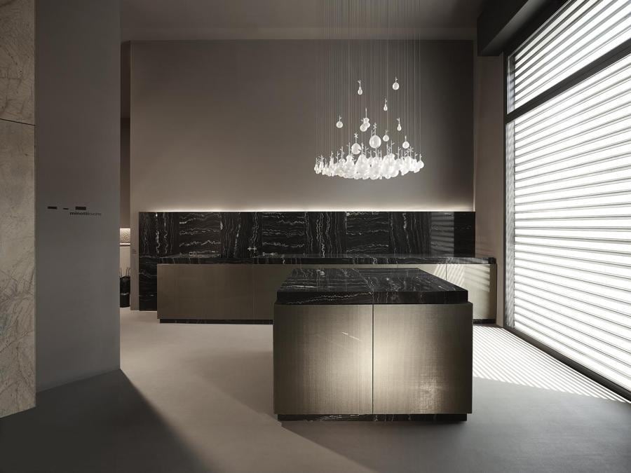minotticucine, Seta, design Alberto Minotti. Cucina con ante formate da due sottilissime ma estremamente resistenti lastre di vetro accostate l'una all'altra, che racchiudono un'anima di seta. La pietra viene proposta in modo inedito: per eliminare la fuga, limite tecnico di questo materiale naturale, la venatura della pietra viene disposta perpendicolare rispetto a quella in fianco e sviluppata per ogni modulo anta. Uno scambio di linee che riprende gli intrecci del tessuto interno alle lastre in vetro. In Seta, le colonne emergono automaticamente dal top portando gli elettrodomestici contenuti al loro interno ad un livello ottimale per essere utilizzati e, una volta terminato l'utilizzo, ritornano invisibili