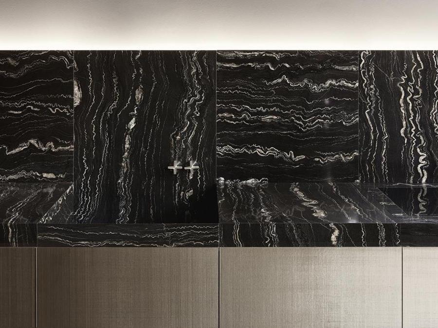 minotticucine, Seta, design Alberto Minotti. Cucina con ante formate da due sottilissime ma estremamente resistenti lastre di vetro accostate l'una all'altra, che racchiudono un'anima di seta. La pietra viene proposta in modo inedito: per eliminare la fuga, limite tecnico di questo materiale naturale, la venatura della pietra viene disposta perpendicolare rispetto a quella in fianco e sviluppata per ogni modulo anta. Uno scambio di linee che riprende gli intrecci del tessuto interno alle lastre in vetro. In Seta, le colonne emergono automaticamente dal top portando gli elettrodomestici contenuti al loro interno ad un livello ottimale per essere utilizzati e, una volta terminato l'utilizzo, ritornano invisibili