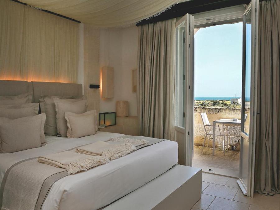 Camera con vista sul mare nell'edificio principale, chiamato la Corte. Gli arredi sono contemporanei eppure evocativi di quelli tradizionali, con letti king size, divano, scrivania in pietra.
