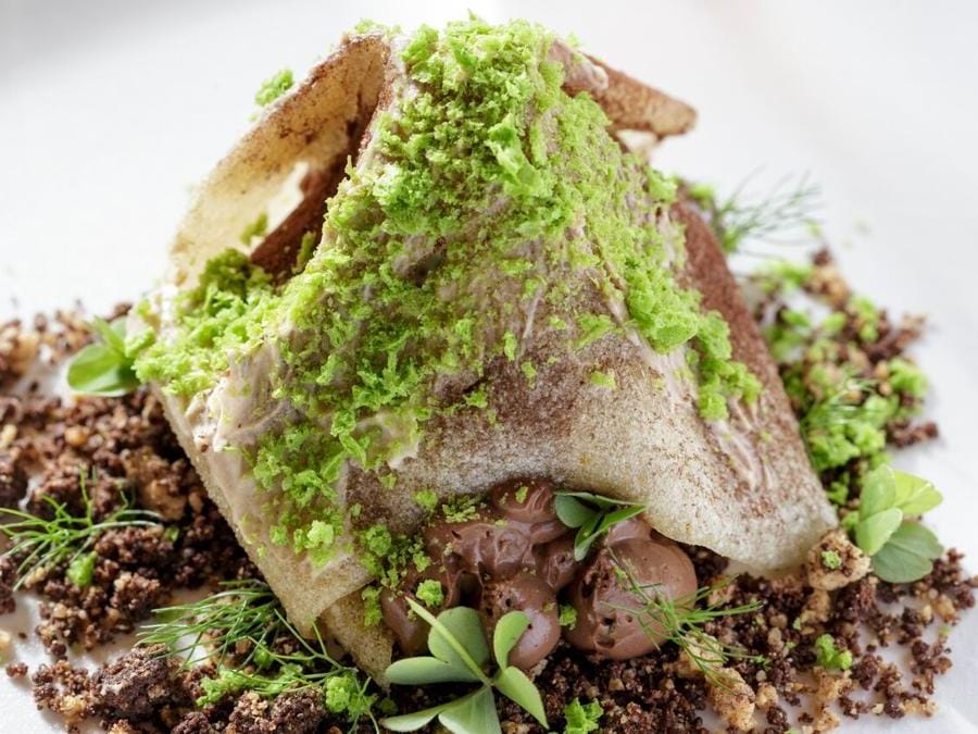 L'impiattamento evoca il paesaggio intorno, come questo Monte Voltraio, una cialda di riso croccante, mousse e crumble al cioccolato, gelato di mandorla e visciole. 