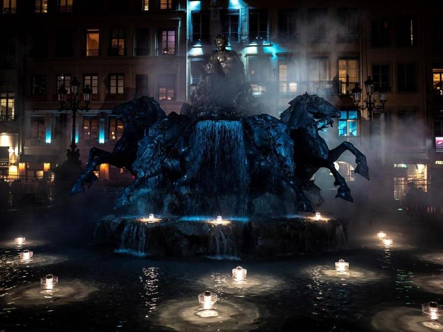 La fontana Bartholdi illuminata a Lione. (Photo by JEAN-PHILIPPE KSIAZEK / AFP)