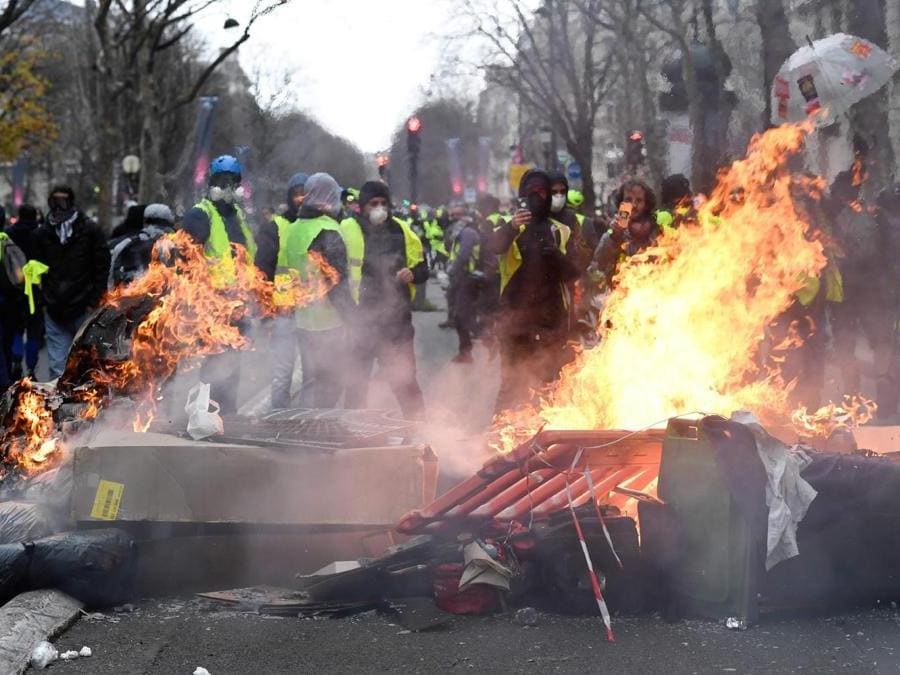 Protestors wearing "yellow vests" (gilets jaunes) stand next to items set on fire near the Champ Elysees avenue as they demonstrate against rising costs of living in Paris on December 8, 2018. - Paris was on high alert on December 8 with major security measures in place ahead of fresh "yellow vest" protests which authorities fear could turn violent for a second weekend in a row. (Photo by Bertrand GUAY / AFP)