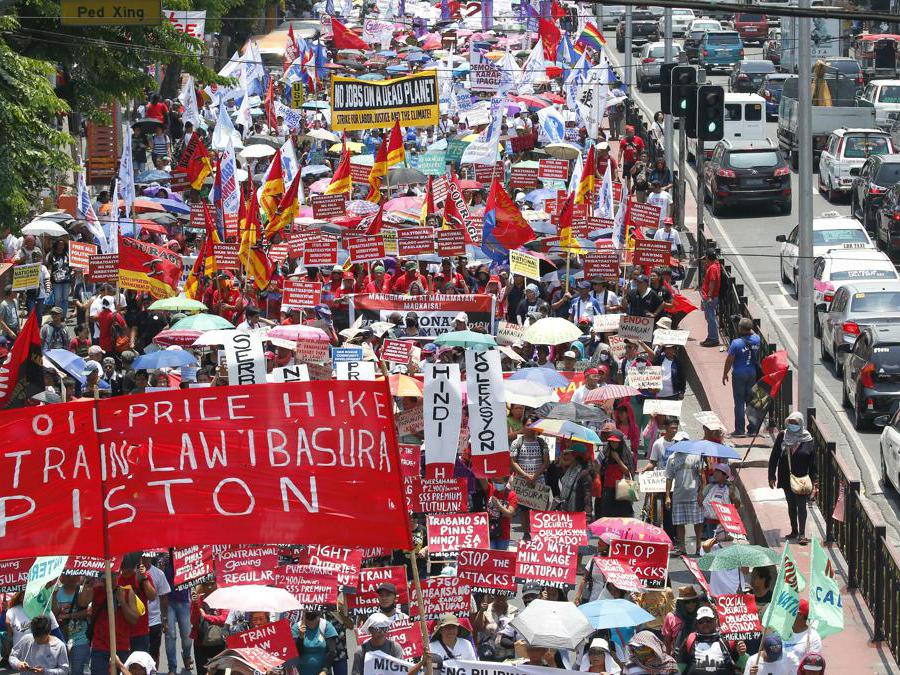 Migliaia di lavoratori manifestano il loro messaggio mentre marciano verso il palazzo presidenziale a Manila, nelle Filippine, per rendere omaggio ai lavoratori in occasione della Giornata internazionale del lavoro. (AP Photo/Bullit Marquez)