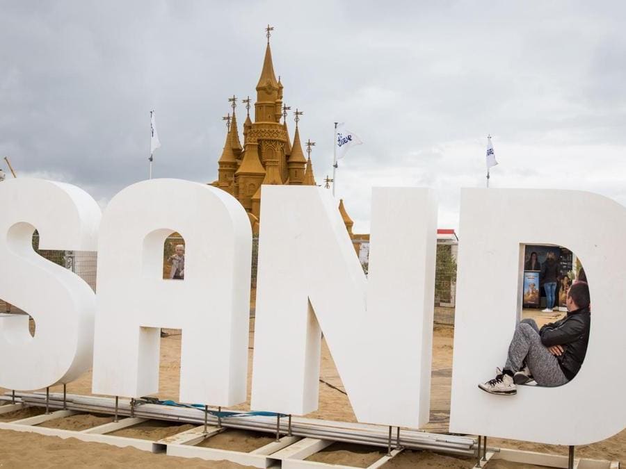 Un uomo siede dentro una lettera gigante davanti a sculture di sabbia che rappresentano personaggi e scene di film Disney durante una mostra Disney Sand Magic a Ostend, Belgio. (Afp)