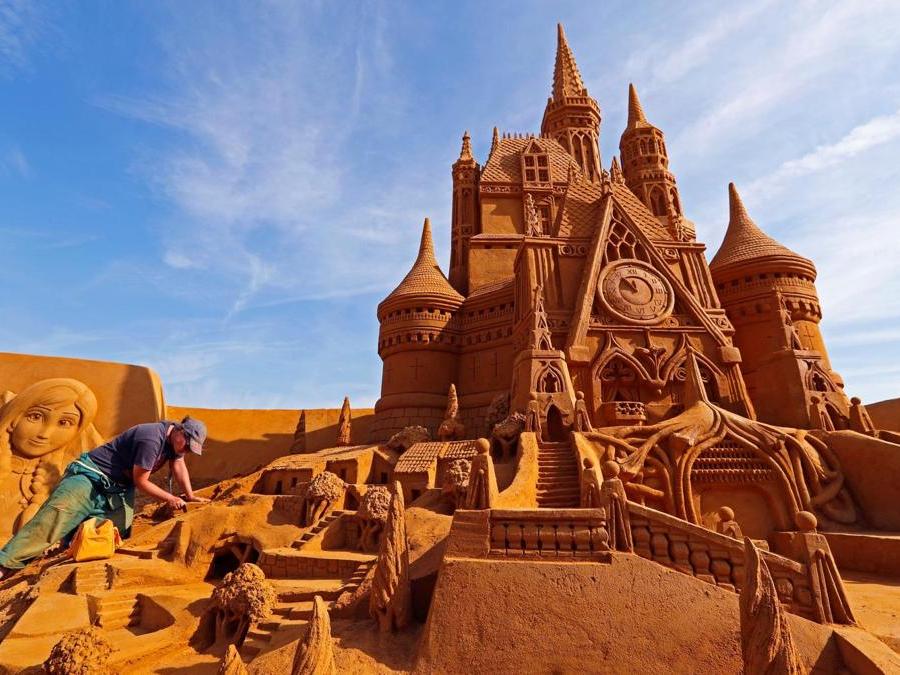 Susanne Paucker dalla Germania lavora su una scultura  durante il Festival della scultura di sabbia “Disney Sand Magic” a Ostenda. (Reuters)