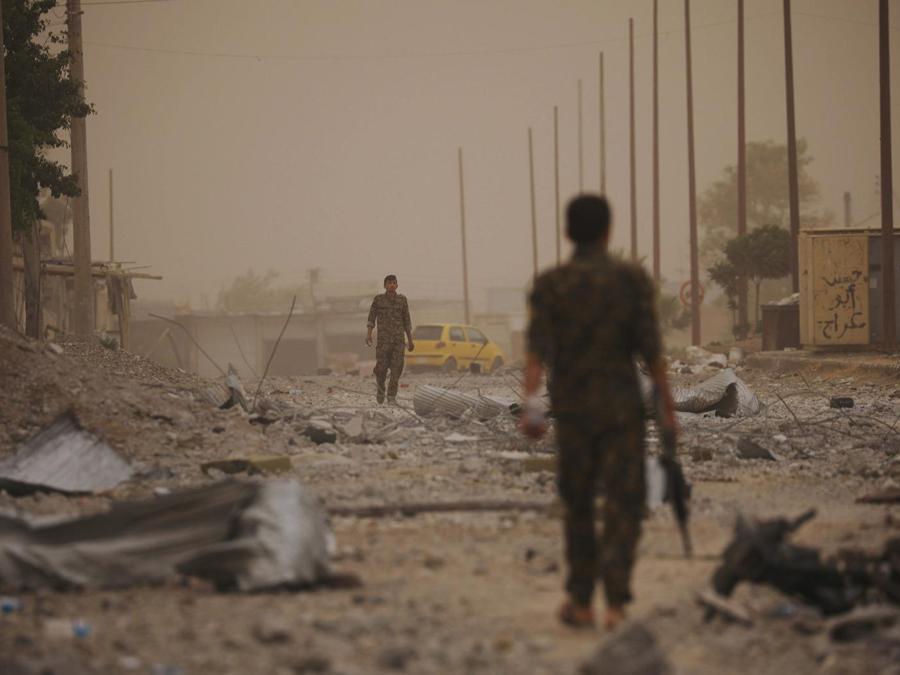 I combattenti delle forze democratiche siriane (SDF) camminano sulle macerie di una strada danneggiata nel quartiere industriale al-Sanaa di Raqqa. (REUTERS/Rodi Said)