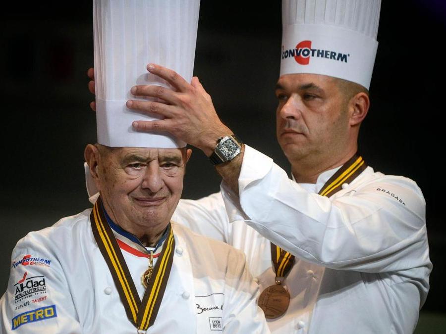 Questa foto di archivio scattata il 30 gennaio 2013 mostra lo chef francese Jerome Bocuse (destra) che aggiusta il cappello del padre Paul Bocuse durante la 14a edizione della finale mondiale della competizione culinaria internazionale del Bocuse d'Or (Golden Bocuse), a Chassieu, Francia. (Afp)