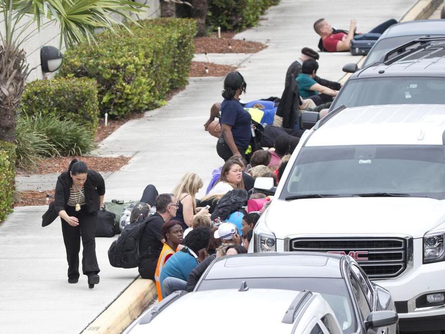 Persone si mettono al riparo dietro le automobili. (AP Photo/Wilfredo Lee)