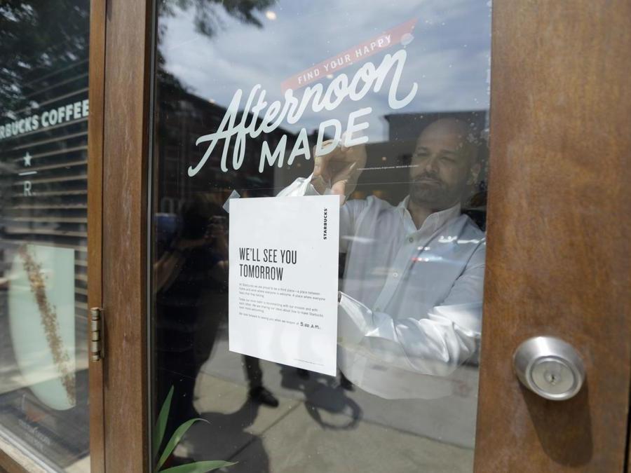 Martedì 29 maggio 2018, a Filadelfia, un uomo appoggia un cartello sulla porta di una caffetteria Starbucks. Dopo gli arresti di due uomini di colore, Starbucks chiuderà più di 8.000 negozi a livello nazionale  per condurre un addestramento anti-pregiudizio, il prossimo dei molti passi che l'azienda sta intraprendendo per provare a ripristinare il suo appannato immagine come un ritrovo dove tutti sono i benvenuti (AP Photo/Matt Slocum)