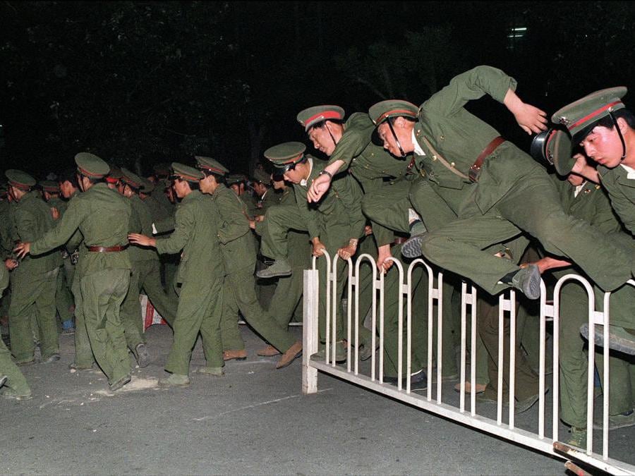 I soldati dell'esercito di liberazione (PLA) oltrepassano una barriera in Piazza Tiananmen, nel centro di Pechino, il 4 giugno 1989, durante i pesanti scontri con persone e studenti dissidenti. THOMAS CHENG / ANSA / LI