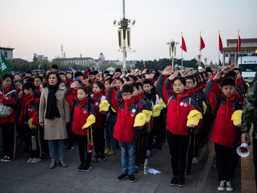 In questa foto, scattata il 1 aprile 2019, gli studenti delle scuole cantano l'inno nazionale durante la cerimonia di innalzamento della bandiera in piazza Tiananmen a Pechino. (Photo by STR / AFP)