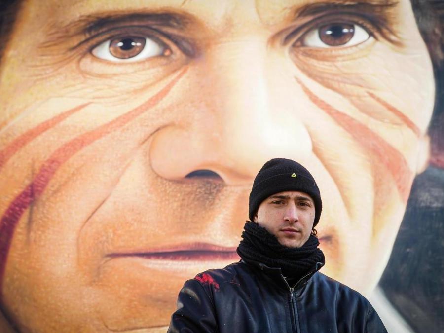 L'artista Jorit Agoch posa davanti al murales dello scrittore e regista Pier Paolo Pasolini nell'ambito di un progetto di riqualificazione delle periferie di Napol, nel quartiere Scampia, 6 febbraio 2019. ANSA/CESARE ABBATE