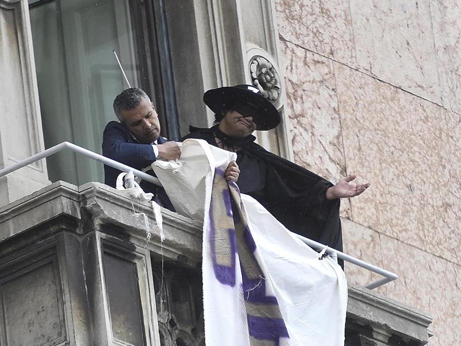Il momento in cui viene rimosso lo striscione di contestazione affisso da un uomo vestito da Zorro durante la manifestazione in piazza Duomo “Prima l'Italia. Il buon senso in Europa”. (Ansa/Flavio Lo Scalzo)