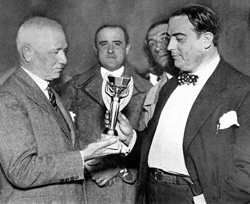 1930. URUGUAY. Il presidente della Fifa (primo a sinistra, foto Afp) con il trofeo realizzato dall'orafo parigino LaFleur, che raffigura una vittoria alata che regge una coppa decagonale, appoggiato a un piedistallo di lapislazzuli a base ottagonale. Il peso complessivo di 3.800 grammi, di cui 1.800 grammi in argento “sterling” placcato oro. Originariamente chiamato Victory, è stato ufficialmente rinominato coppa Rimet nel 1946. Il trofeo fu messo in palio la prima volta a Montevideo nel 1930. In base al regolamento Fifa la coppa è stata assegnata definitivamente al Brasile nel 1970, in quanto prima nazione ad averla vinta  per tre volte. 