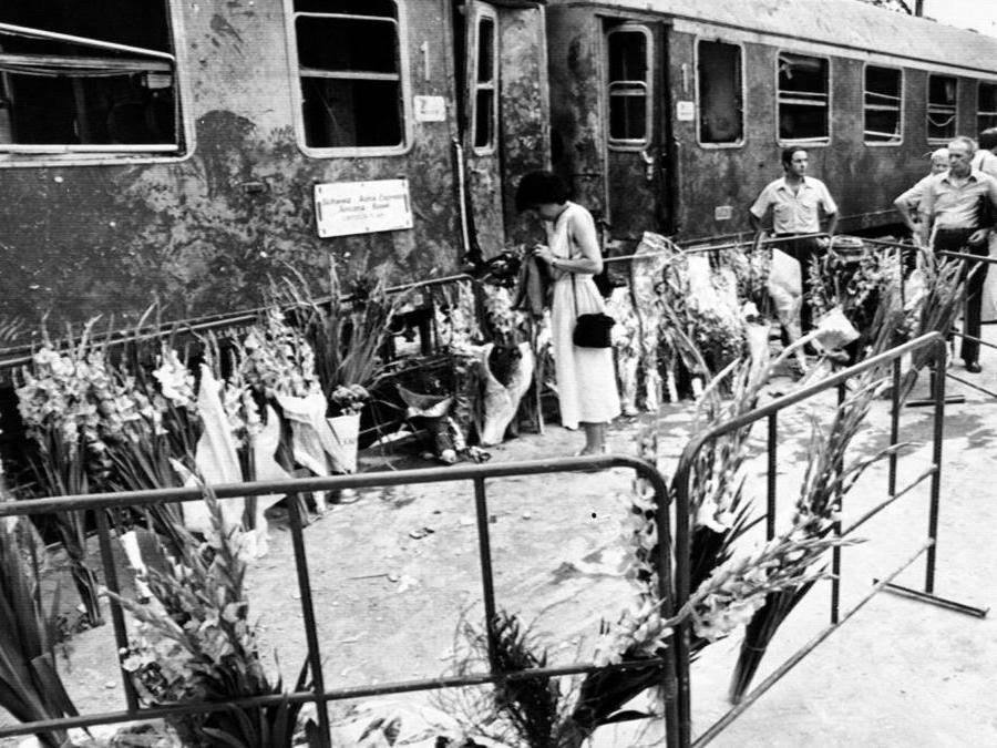 I fiori portati dai cittadini davanti alla carrozza dell'Adria Express dopo la strage di Bologna del 2 agosto 1980. ANSA.