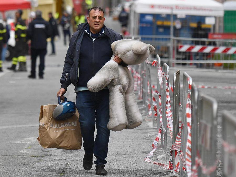 Uno sfollato trasporta un orso appartenuto ai suoi figli nel giorno della ripresa delle operazioni per consentire agli sfollati di entrare nelle loro case per l'ultima volta, per poter recuperare le ultime cose, Genova. ANSA/LUCA ZENNARO