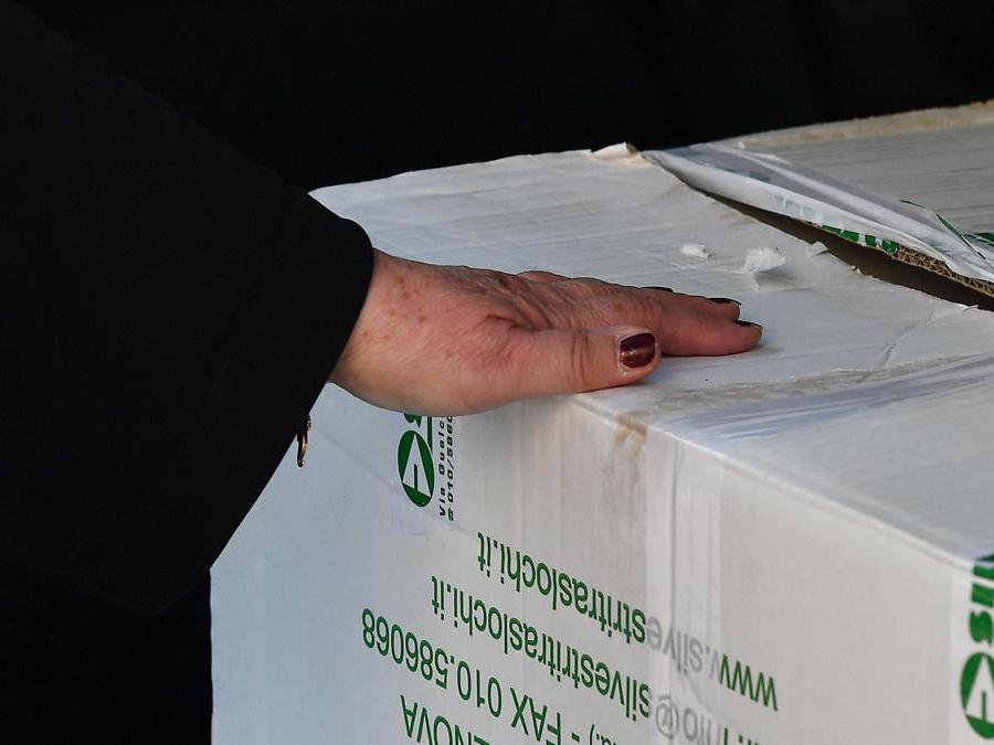La mano di una signora sfollata tiene la scatola con le sue cose recuperate e stipate in auto. Genova. ANSA/LUCA ZENNARO