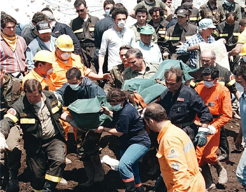 Una vittima della frana di Sarno viene portata via dalle rovine della sua casa sotto gli occhi delle tante persone impegnate nei lavori di scavo. (Ciro Fusco)