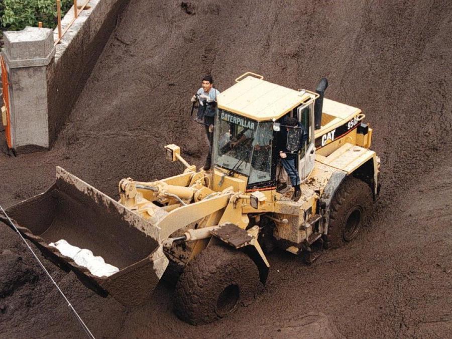Una pala meccanica si fa strada a Sarno tra un mare di fango dopo il recupero di una salma. (Ciro Fusco)