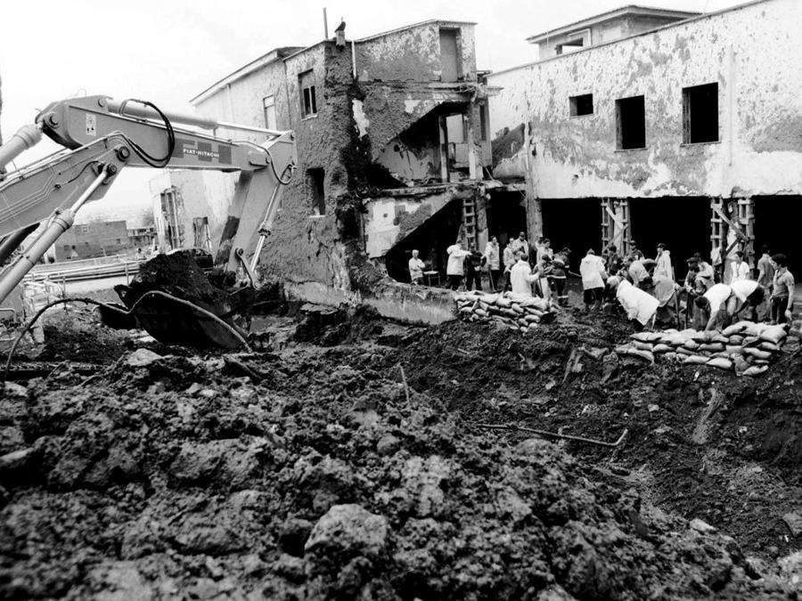I volontari della Protezione Civile ed i Vigili del Fuoco approfittano di una tregua delle condizioni meteoreologiche per la pulizia e la costruzione di un argine di uno dei canali per il deflusso delle acque piovanea Sarno. (ANSA)
