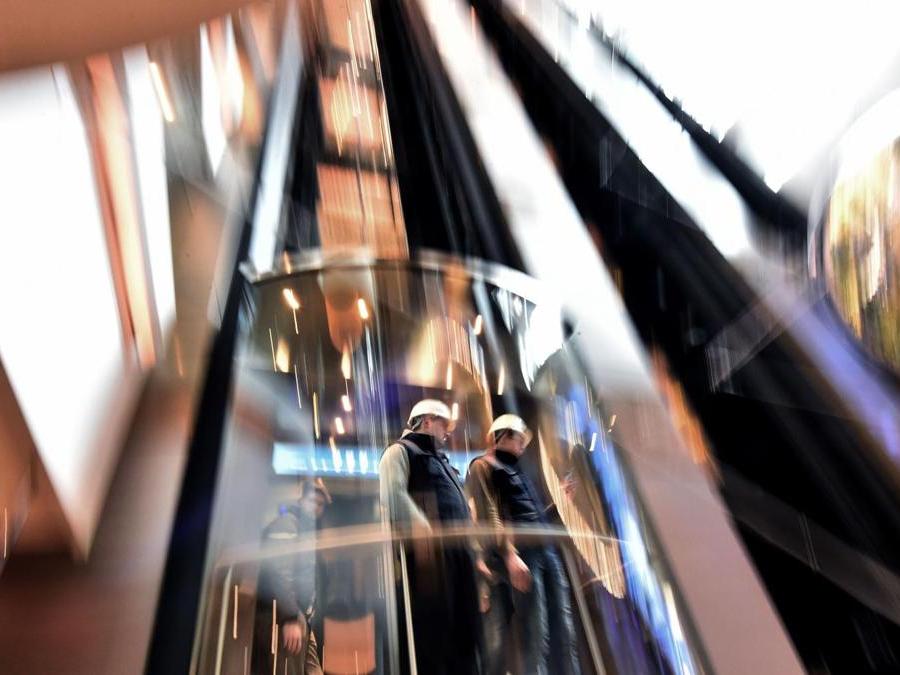 STX and RCCL employees arrive by elevator to attend a delivery ceremony of tourism cruise liner 'Symphony of the Seas' from the STX shipyards to an American company 'Royal Caribbean' on March 23, 2018 at the shipyard of Saint-Nazaire, western France. / AFP PHOTO / LOIC VENANCE