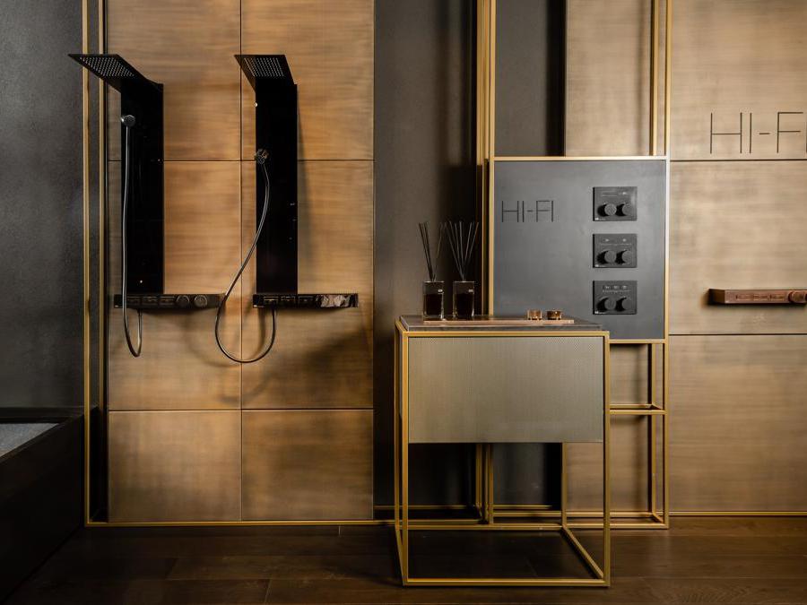 Gessi, H-Fi. Sistema di selezione di funzioni, portata e mixer termostatico della doccia che riprende l'estetica di un impianto stereo anni '90. I mixer termostatici a pulsante a incasso o esterni sono funzionali e minimalisti. Le colonne doccia del Sistema Hi-Fi di Gessi, con il loro design lineare, stravolgono il concetto di colonna ibridandola con le forme tipiche del pannello doccia, ma con installazione totalmente esterna, senza elementi ad incasso. La sezione di colonna/pannello, in vetro sottile 4 mm, come la mensola, si trova disassata rispetto a quest'ultima che contiene anche i comandi termostatici. Disponibili con funzionalità pioggia, cascata e kit doccia direzionabile, sono dotate anche di una doccetta a mano agganciata con sistema magnetico e posizionabile a piacere