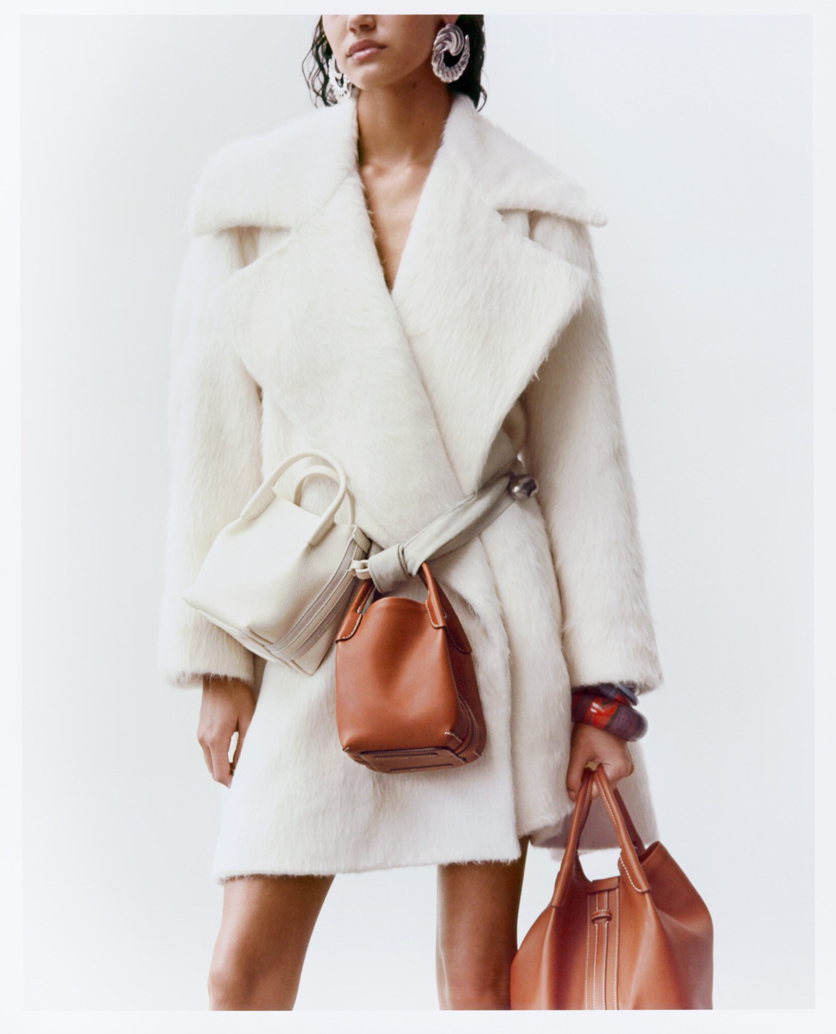 Borse Bale Micro (2.400 €) e borsa grande Bale in pelle (3.400 €). Tutto LORO PIANA. Bracciali rigidi in legno laccato, HERMÈS (da 175 € a 245 €). Cappotto in lana e alpaca, LOEWE (2.950 €).