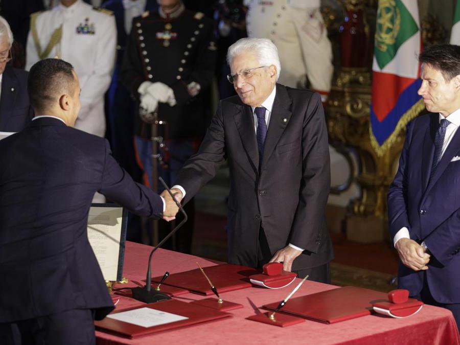 Il ministro degli Esteri Luigi Di Maio, a sinistra, stringe la mano al presidente Sergio Mattarella, al centro, mentre il Primo Ministro Giuseppe Conte osserva. (AP Photo/Andrew Medichini)