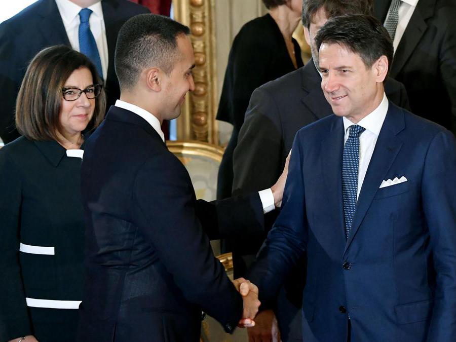 Il Ministro degli Esteri Luigi Di Maio (centro) stringe la mano al Primo Ministro Giuseppe Conte (destra) sotto lo sguardo del Ministro delle Infrastrutture e dei trasporti Paola De Micheli. (Photo by Andreas SOLARO / AFP)