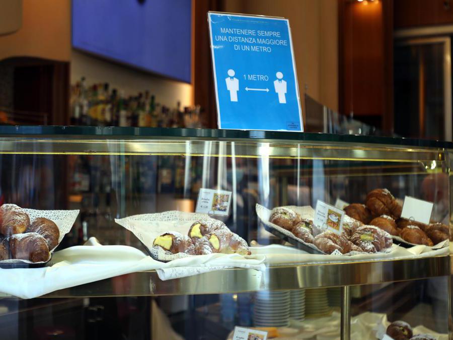 Un cartello che ricorda la regola del distanziamento esposto in un bar in corso Vittorio Emanuele nel giorno della riapertura delle attività commerciali, Milano, 18 maggio 2020. ANSA / MATTEO BAZZI