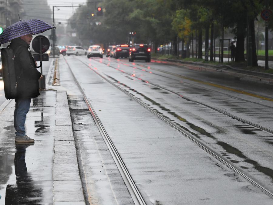 Una persona attende l'arrivo di un tram a una fermata (Ansa/Daniel Dal Zennaro)