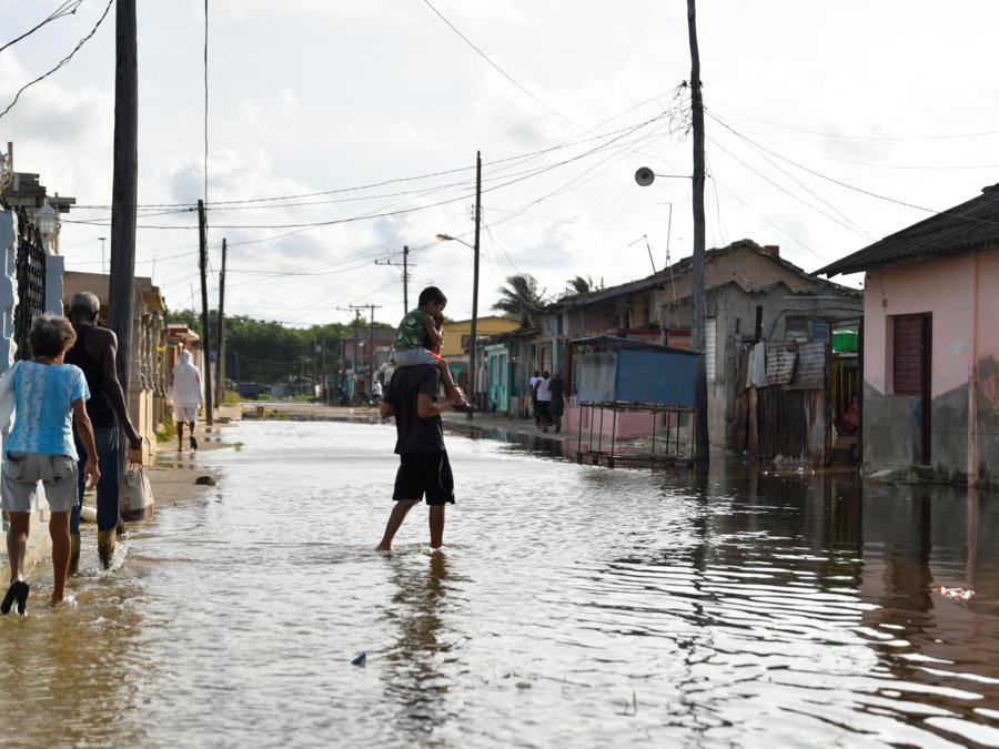 Un uomo con un bambino attraversa una strada allagata mentre l’uragano Milton si avvicina alla costa cubana a Batabano, Cuba. (Reuters)